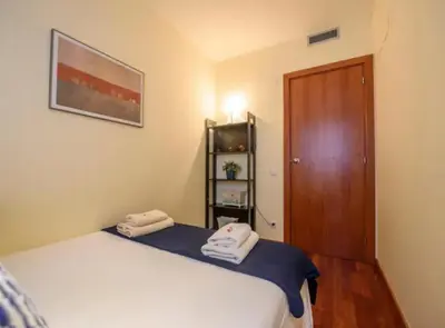 a small room with a bed and a wooden door at RamblasRentals Stylish Bright 3BR New Catalan Flat 10m Ramblas - Parking - Wifi in Barcelona