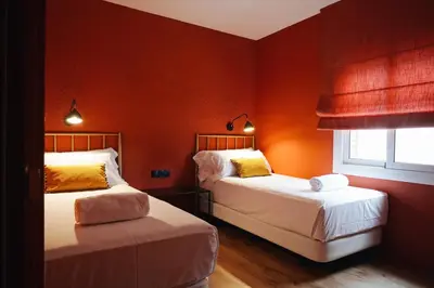 two beds in a room with orange walls at Isabella's House in Barcelona