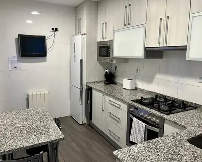 a kitchen with a stove and a refrigerator at Amplio Apartamento cerca de FIRA y del Centro in Hospitalet de Llobregat