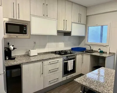 a kitchen with white cabinets and a stove top oven at Amplio Apartamento cerca de FIRA y del Centro in Hospitalet de Llobregat