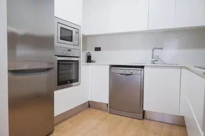 a kitchen with stainless steel appliances and white cabinets at Apartments Hotel Sant Pau in Barcelona