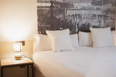a bedroom with a white bed with a black and white picture at Apartments Hotel Sant Pau in Barcelona