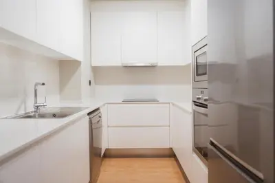 a white kitchen with a sink and a refrigerator at Apartments Hotel Sant Pau in Barcelona