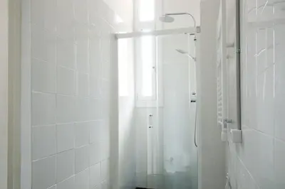 a white bathroom with a shower and a window at My Address in Barcelona in Barcelona