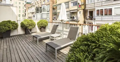 a balcony with two chairs and a umbrella on a building at Murmuri Residence Concepció in Barcelona