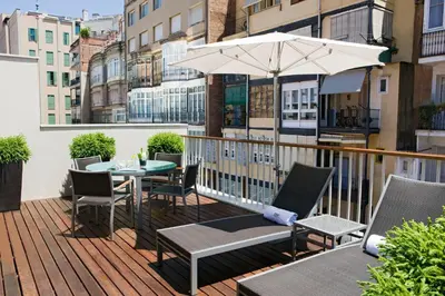 a patio with a table and chairs and an umbrella at Murmuri Residence Concepció in Barcelona