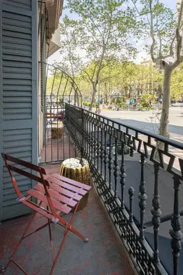 a red bench sitting on a porch next to a fence at Hotel Casa Trafalgar Barcelona in Barcelona