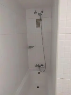 a shower in a white bathroom with a shower head at Luxury Apartment Accommodation, next to beach & train station Calella in Calella
