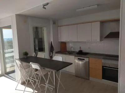 a kitchen with white cabinets and a table and chairs at Luxury Apartment Accommodation, next to beach & train station Calella in Calella