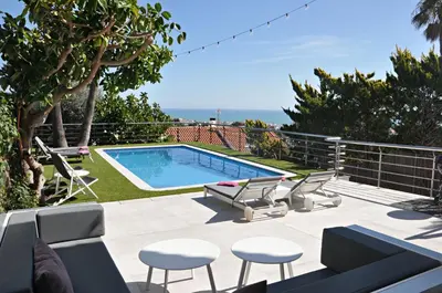 a patio with a swimming pool and chairs and the ocean at Miramar Sitges in Sitges