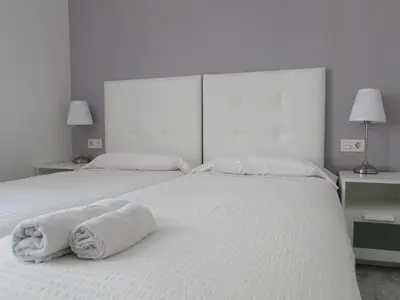 a white bed with two towels on top of it at Pensió Cerdanya in Barcelona