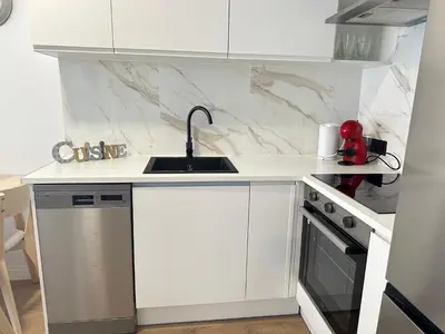 a white kitchen with a sink and a dishwasher at Beach apartment IV Coeur de Plage in Castelldefels