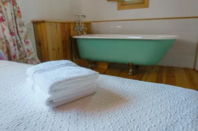 a stack of towels on a bed with a bath tub at Masia Pou de la Vinya in Sitges