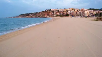 a beach with a group of people walking on it at Hostal Portofino in Arenys de Mar