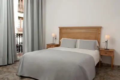 a bedroom with a large white bed with two lamps at Hostal Portofino in Arenys de Mar