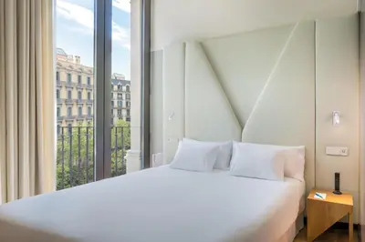 a bedroom with a white bed and a large window at Occidental Diagonal 414 in Barcelona