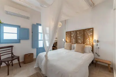 a white bedroom with a white bed and a chair at Casa Azul by Hello Homes Sitges in Sitges