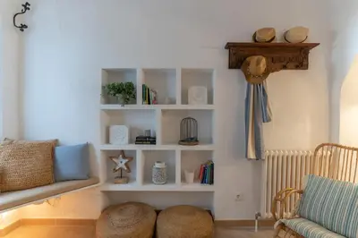 a living room with white shelves and a chair at Casa Azul by Hello Homes Sitges in Sitges