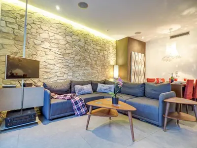a living room with a blue couch and a stone wall at Chic by Hello Homes Sitges in Sitges