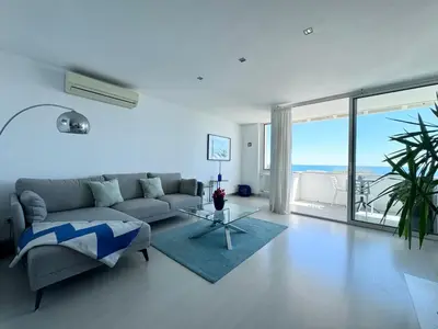 a living room with a couch and a large window at Vistas Del Mar by Hello Homes Sitges in Sitges