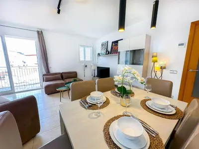 a dining room and living room with a table and chairs at Sunlight by Hello Homes Sitges in Sitges