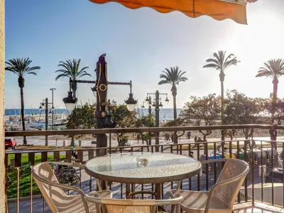 a table and chairs on a balcony with palm trees at Soleil by Hello Homes Sitges in Sitges