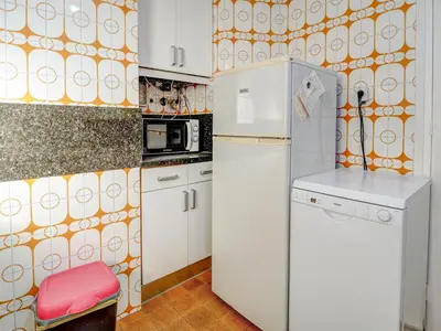 a kitchen with a white refrigerator and a red stool at Soleil by Hello Homes Sitges in Sitges