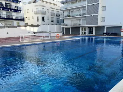 a large blue swimming pool in front of buildings at Diamond by Hello Homes Sitges in Sitges