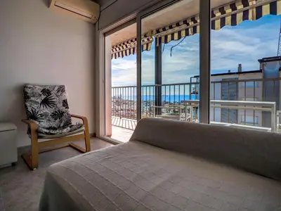 a bedroom with a bed and a chair and a large window at Diamond by Hello Homes Sitges in Sitges