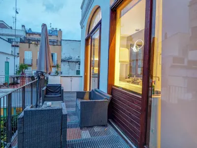 a balcony with chairs and an umbrella on a building at En Vogue by Hello Homes Sitges in Sitges