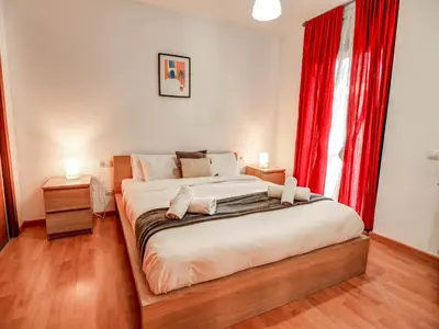 a bedroom with a large bed with red curtains at Mimosa Apartment by Hello Homes Sitges in Sitges