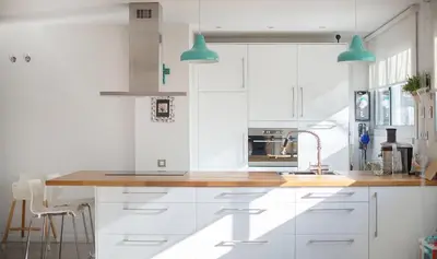 a kitchen with white cabinets and blue pendant lights at Magnificent apartment close to the beach in Barcelona