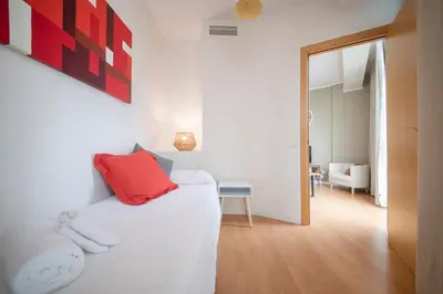 a bedroom with a white bed with a red pillow at You Stylish Sagrada Familia Apartments in Barcelona