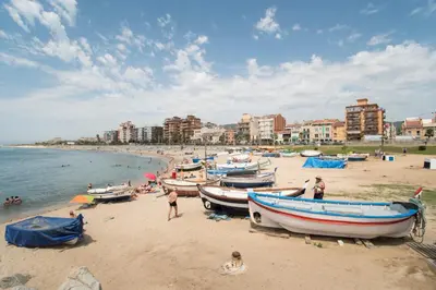 people on a beach with boats on the sand at Vilamarlux IV in Vilassar de Mar