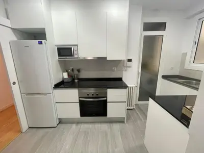 a small kitchen with white cabinets and a refrigerator at Family-Friendly Home in Central Barcelona 4BDR in Barcelona