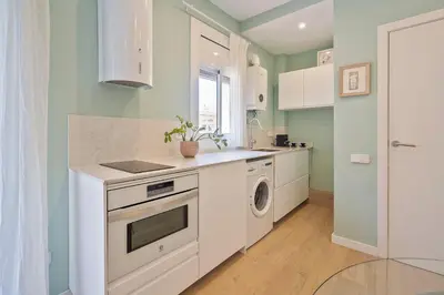 a kitchen with white cabinets and a washer and dryer at Easystaybcn2 in Barcelona