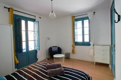 a bedroom with a bed and two windows and a door at LOVELY FLAT FIRA MWC in Hospitalet de Llobregat
