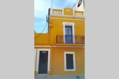 a yellow building with a balcony and a door at LOVELY FLAT FIRA MWC in Hospitalet de Llobregat