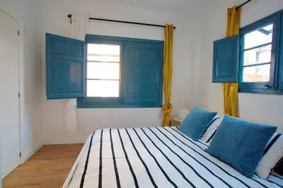 a bedroom with blue windows and a large bed at LOVELY FLAT FIRA MWC in Hospitalet de Llobregat