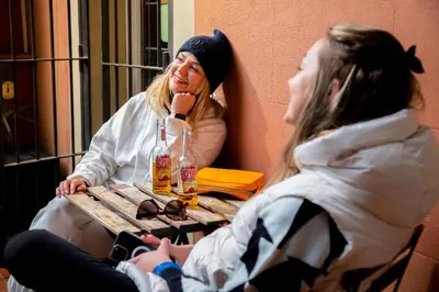 two women sitting at a table with drinks at Casa Barcelo Hostel Barcelona in Barcelona