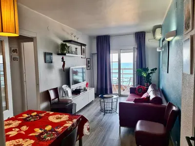 a living room with a couch and a table and a tv at Apartment in front of the Beach in Pineda de Mar