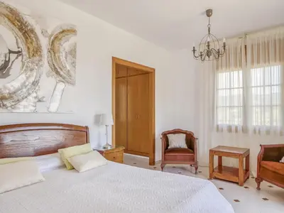 a bedroom with a bed and a chair and a chandelier at Villa in Arenys de Mar with Sea View in Arenys de Mar