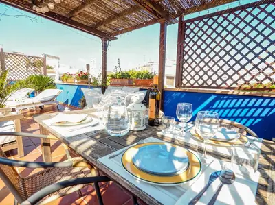 a table with plates and glasses on a balcony at Montroig Zen Penthouse by Hello Homes Sitges in Sitges