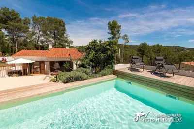 a swimming pool with two chairs and a house at Villa Falco is a beautiful single storey holiday villa with private pool in Viladellops
