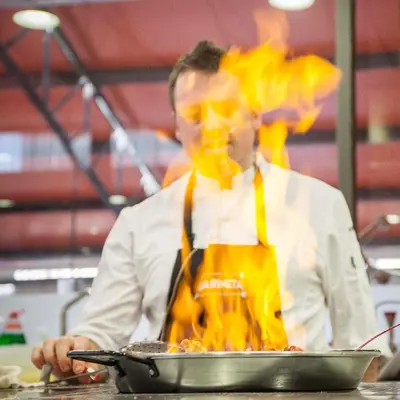 a man in a kitchen preparing food in a pan at Mataró Center Apartment in Mataró