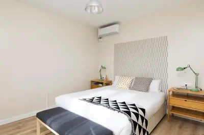 a bedroom with a large white bed with a bench at Casa Cosi - Sants in Barcelona