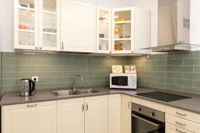 a kitchen with white cabinets and a sink and a microwave at Modernist Family Apartment by PriorityVillas in Barcelona