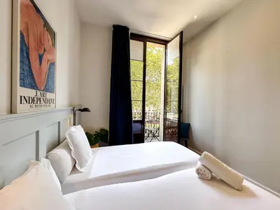 a bedroom with two white beds and a window at Som Nit Born in Barcelona