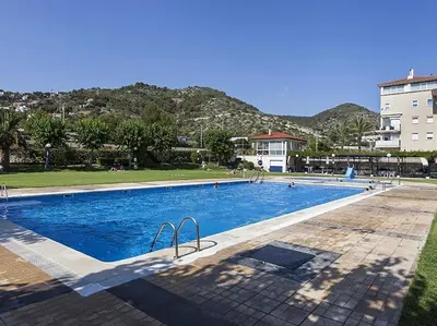 a large swimming pool with mountains in the background at La Marina Sea Front by Hello Homes Sitges in Sitges