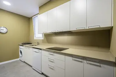 a kitchen with white cabinets and a dishwasher at Ola Living Diagonal II Apartments in Barcelona
